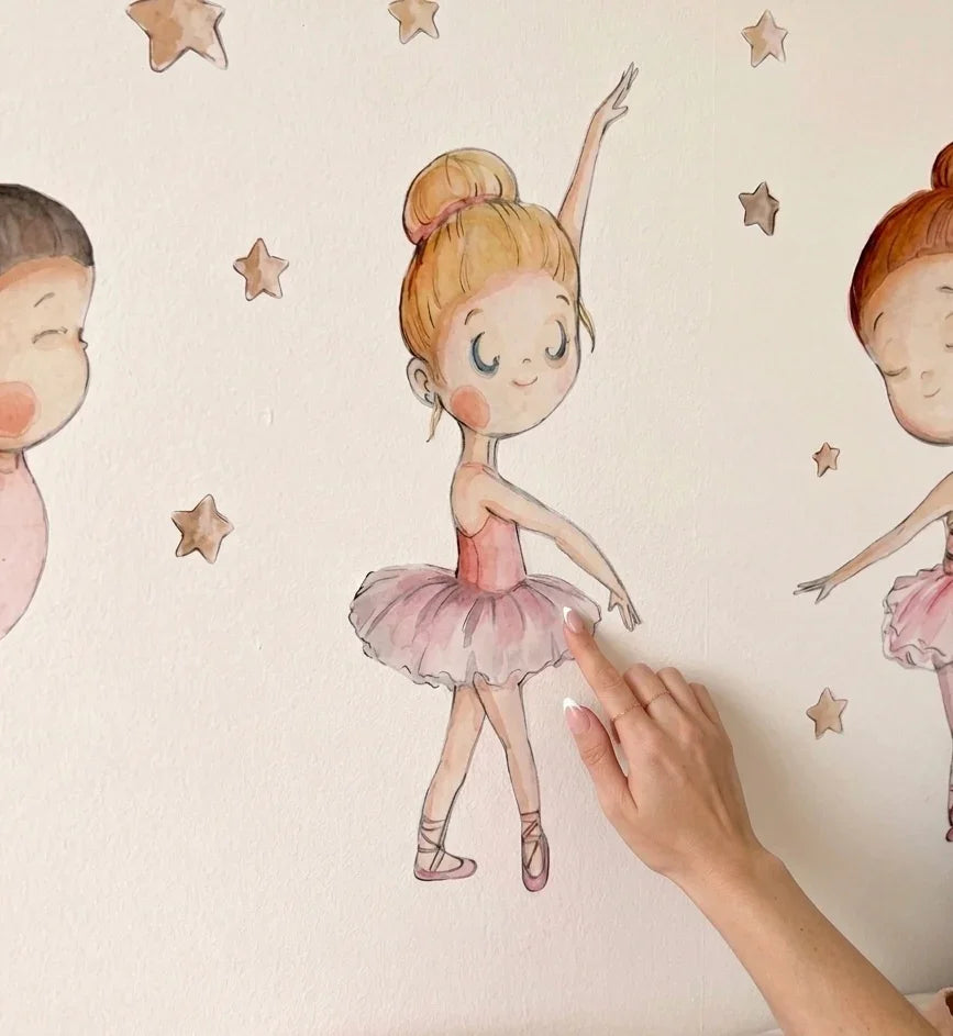 A hand gently touches a whimsical wall mural featuring three charming ballet dancers, each in a graceful pose, surrounded by small stars. The soft colors and delicate details create a magical atmosphere, perfect for a childs room.