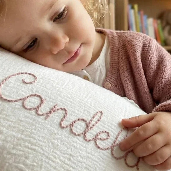 Niña apoyada sobre cojín personalizado bordado con volante