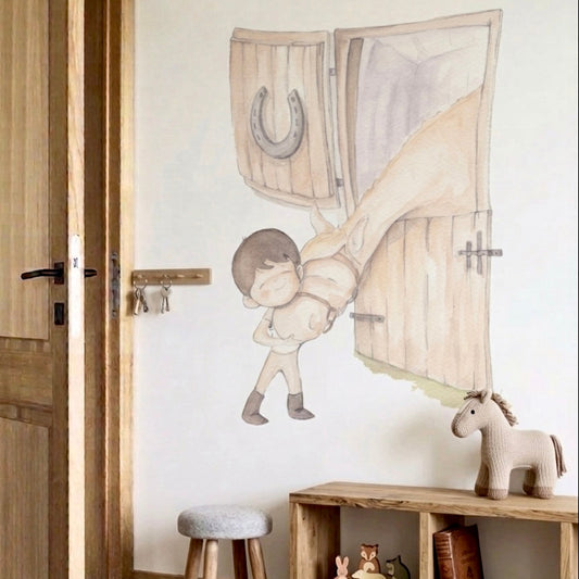 Vinilo decorativo infantil que representa a un niño abrazando un caballo frente a una puerta de establo.