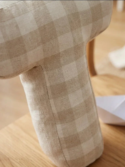 Soft beige gingham-patterned plush toy in a cozy nursery setting on wooden surface