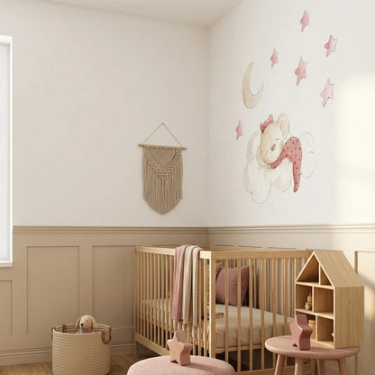 Habitación infantil con cuna de madera, decorada con un vinilo de osita en la nube y estrellas rosas en la.